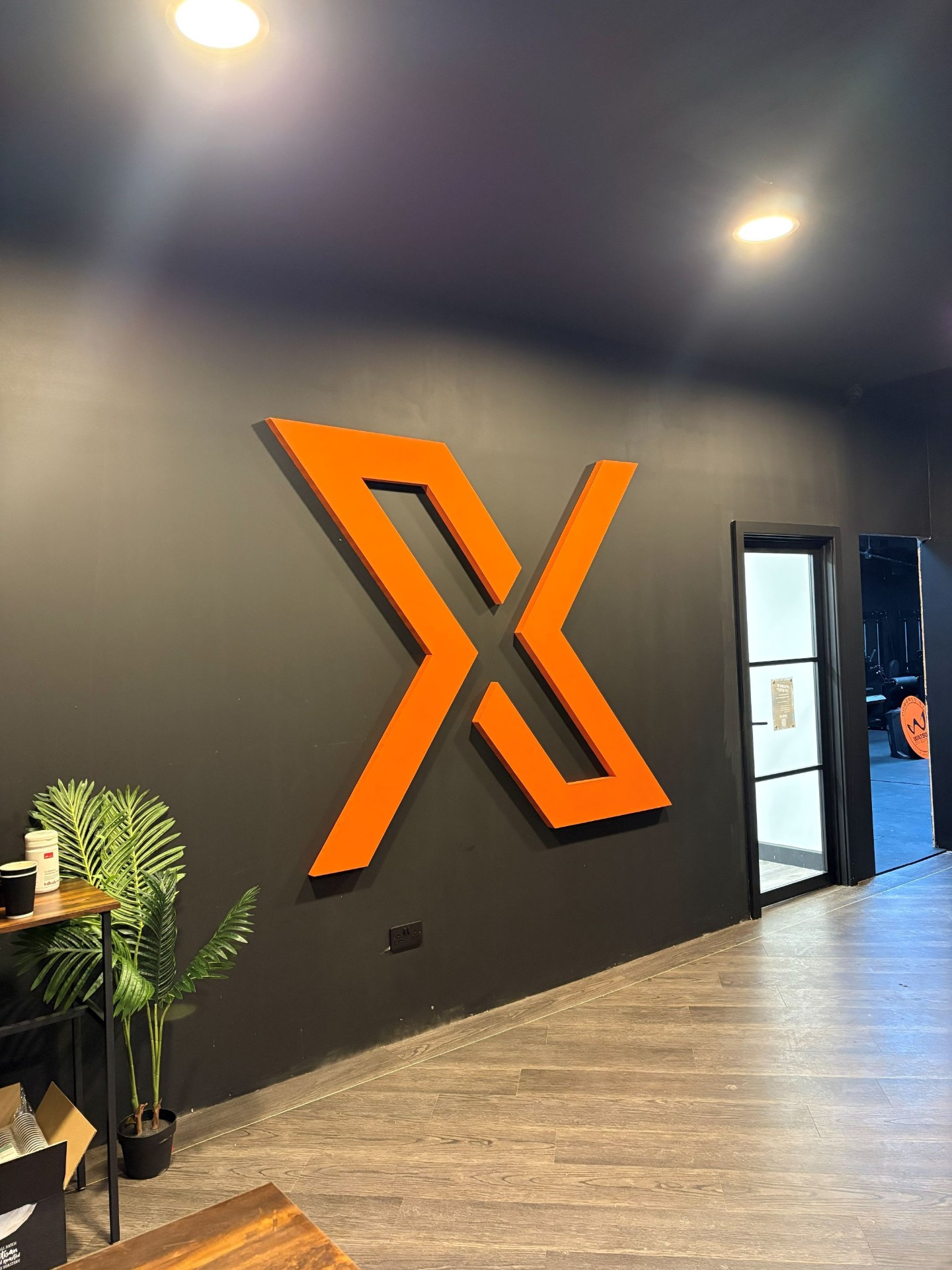 Large orange 3D logo sign mounted on a dark interior wall